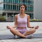 relaxed-calm-woman-sits-lotus-pose-fitness-mat-meditates-listens-pleasant-music-via-headphones-practices-yoga-urban-setting-wears-sportsclothes-keeps-eyes-closed-breathes-deeply (1)